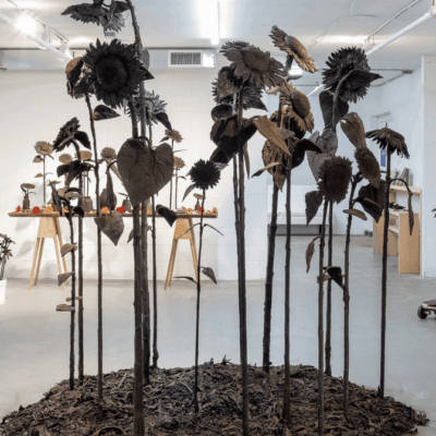 Tall, dark, metallic flower sculptures arranged indoors.