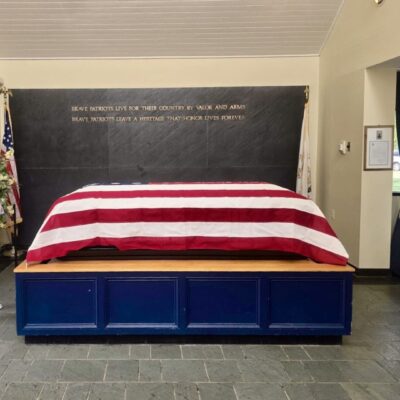 A striped red and white blanket on a bed with a chalkboard headboard.