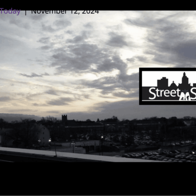 Cityscape at dusk with cloudy skies and silhouetted buildings.