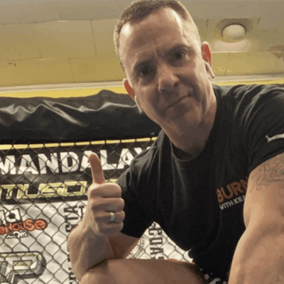 Man giving a thumbs-up in a gym setting.