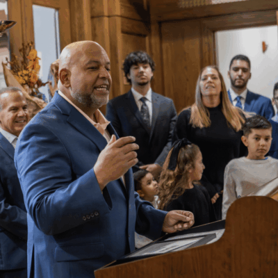 Man speaking at a podium during a formal event with attentive audience.