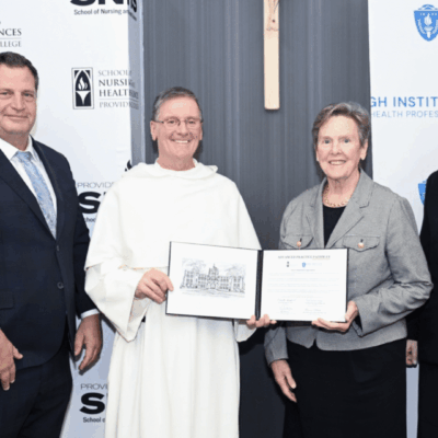 Three people holding an award certificate and smiling at a formal event.