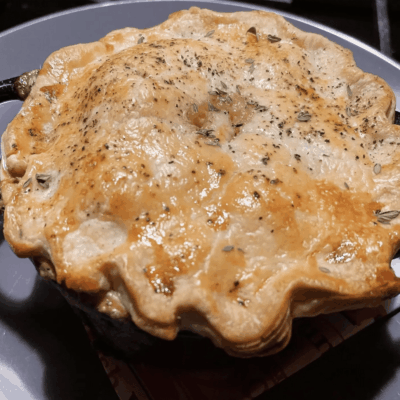 Golden-brown homemade pot pie with a flaky crust sprinkled with herbs.