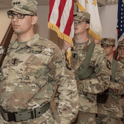Soldiers in uniform standing in formation indoors.