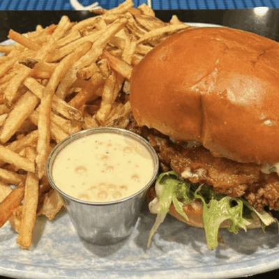 Crispy fried chicken sandwich with lettuce and a side of French fries.