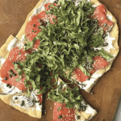 Flatbread topped with smoked salmon, cream cheese, capers, and fresh greens.