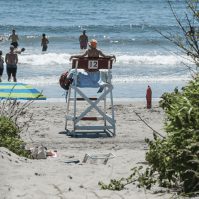 Lifeguard on duty watches over beachgoers enjoying the ocean.