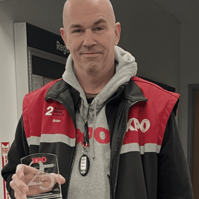 Man in a red and black jacket holding a glass, smiling.