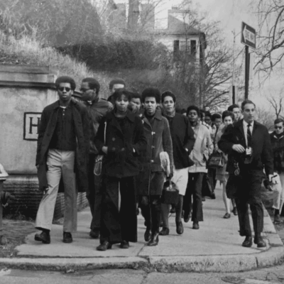 Black and white photo of protestors marching on a city street.