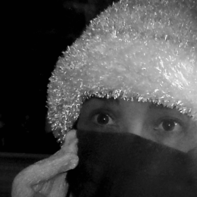 Person wearing a fuzzy hat and face covering in black and white.