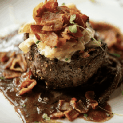 Gourmet steak topped with bacon and creamy sauce.