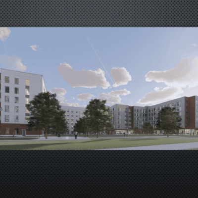 Modern residential buildings surrounding a spacious green courtyard under a blue sky.