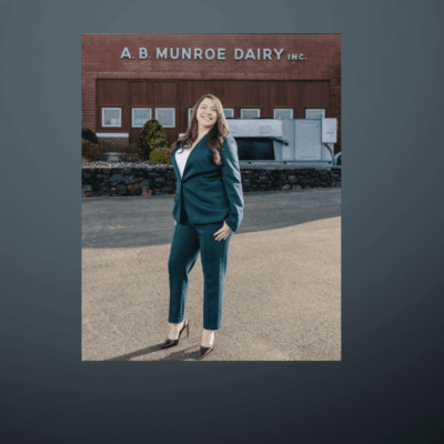 Woman in teal suit standing outdoors in front of a building.