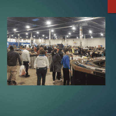 People explore a large indoor market filled with various goods and bright overhead lights.