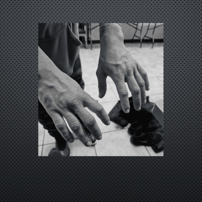 Black and white image of aged hands holding chess pieces.