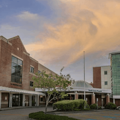 Modern brick and glass buildings under a cloudy sky at sunset.