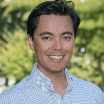 Smiling man outdoors in a light blue shirt.