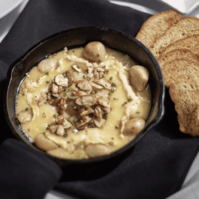 Baked Brie topped with roasted garlic, glazed almonds, and spiced honey served with crostini