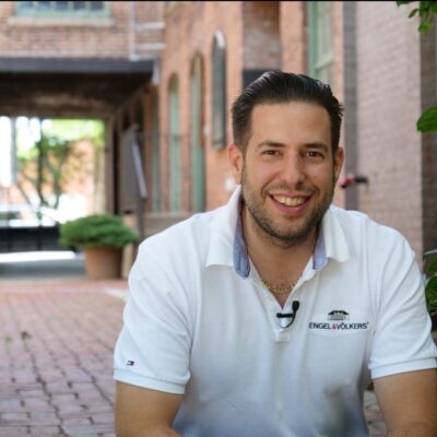 A real estate man in a white shirt sitting on a brick walkway.