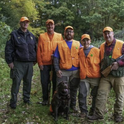 A group of hunters posing for a photo in the woods.