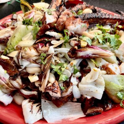 A red plate with a salad on it.