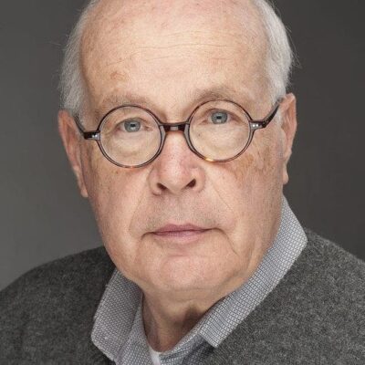 An older man wearing glasses and a sweater.