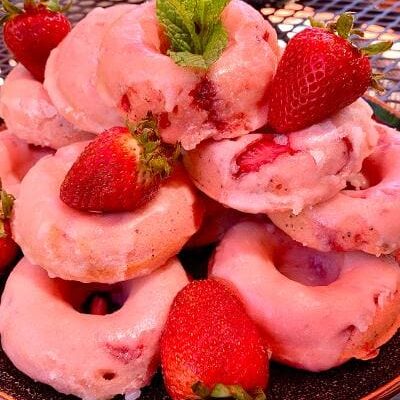 A plate of donuts topped with strawberries and mint.