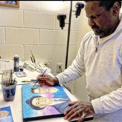 A man creating art by painting a portrait of a man and a woman.