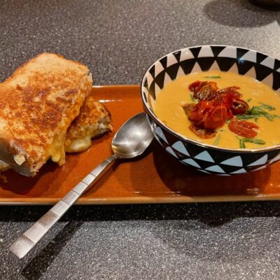 A plate with a grilled sandwich and soup on it, offering delicious recipes.