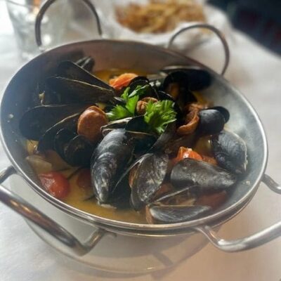 A bowl of mussels and tomatoes on a table, perfect for seafood recipes.
