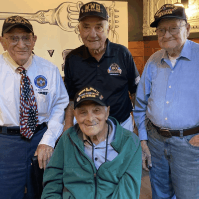Four WWII veterans smiling together.