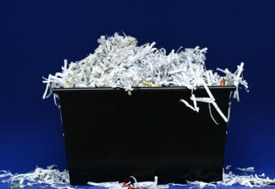 Shredded paper in a black bin on a blue background.