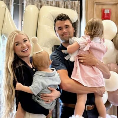 A smiling couple each holding a toddler indoors.