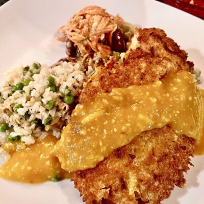 A plate with chicken, rice and gravy on it.