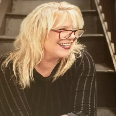 Smiling blonde woman wearing glasses.