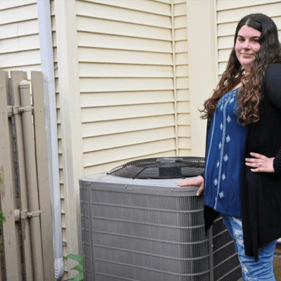 Woman standing next to an outdoor air conditioning unit.