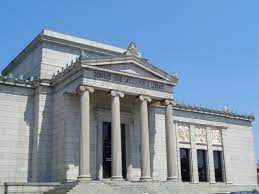 A large white building with columns and a car parked in front of it.