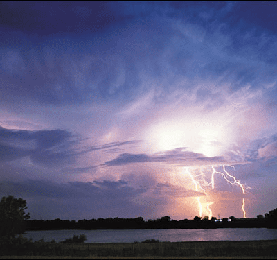 A lightning bolt is seen over a body of water.