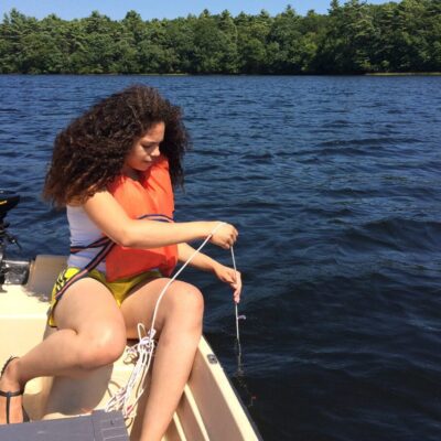 A woman in a life jacket sitting on a boat.