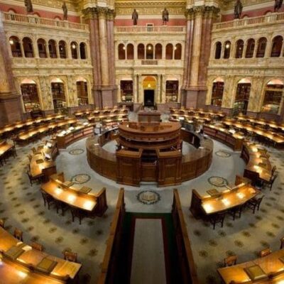 The inside of a library with many tables and chairs.
