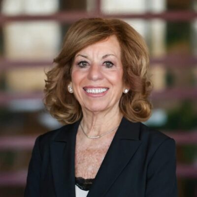 Professional woman with curly hair smiling in an indoor setting.
