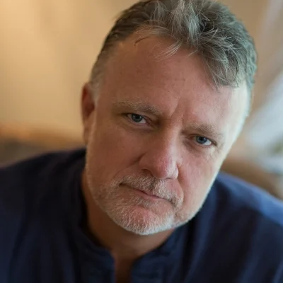 A man in a blue shirt is staring at the camera.