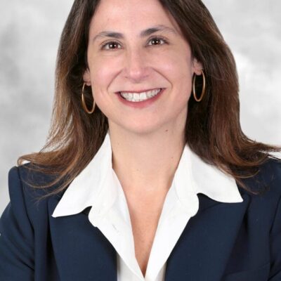 A woman in a business suit smiling, enjoying a moment in her successful lifespan.