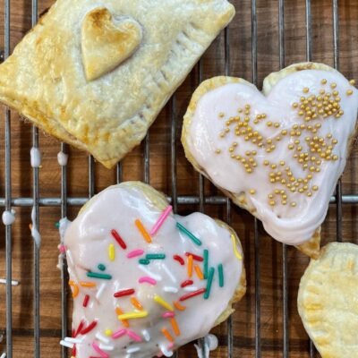 Four heart shaped pastries on a cooling rack.