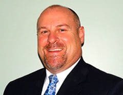 A man in a suit and tie smiling.