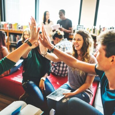 Young people giving high-fives in a lively library setting.