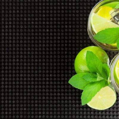 Two glasses of lemonade with mint leaves on a black background.
