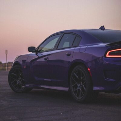 A purple dodge charger parked in a parking lot at sunset.