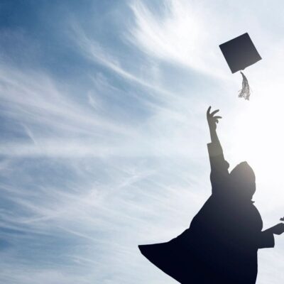 A silhouette of a person tossing a graduation cap in the air.