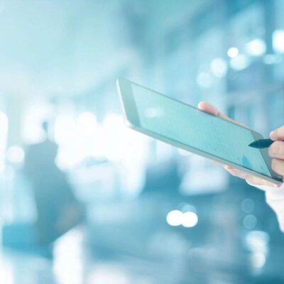 A doctor is holding a tablet in his hand.